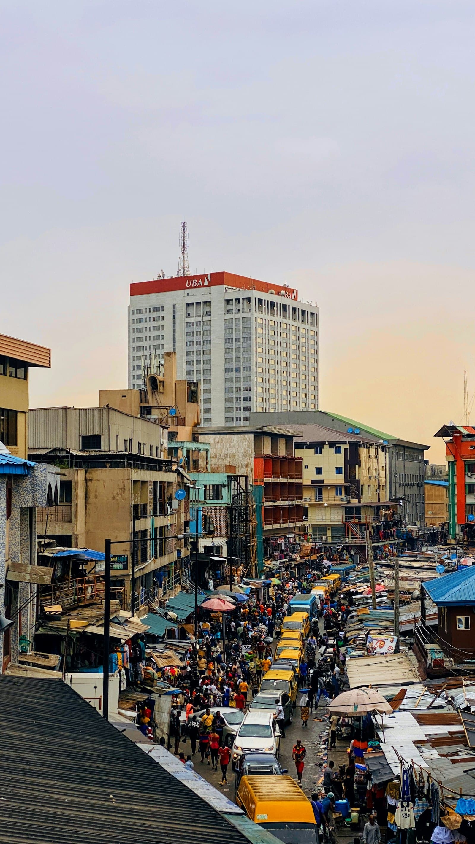 A view over a Lagos market with a UBA bank tower on the skyline.